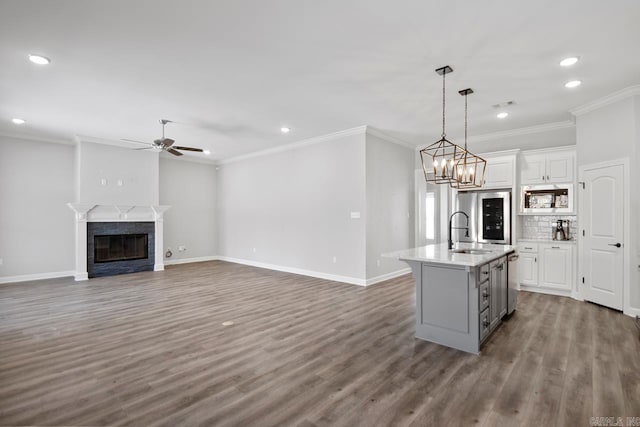 kitchen featuring white cabinets, an island with sink, stainless steel refrigerator, pendant lighting, and built in microwave