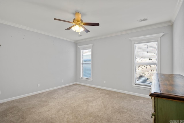 carpeted spare room featuring ceiling fan, crown molding, and a healthy amount of sunlight