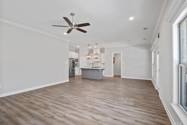 unfurnished living room with sink, hardwood / wood-style floors, ceiling fan, and ornamental molding