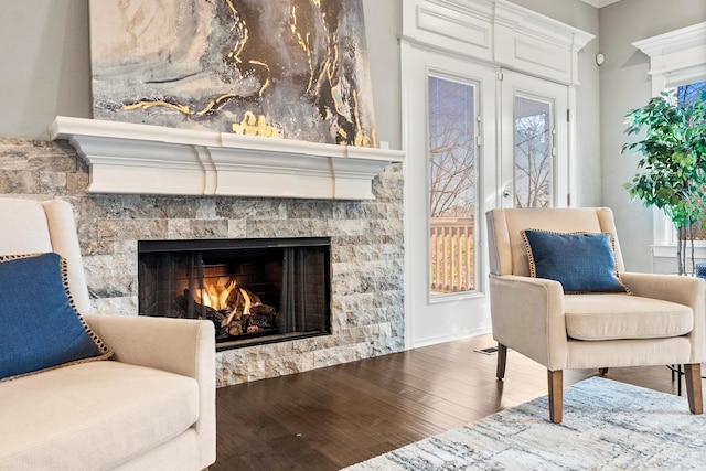 sitting room with wood-type flooring and a stone fireplace