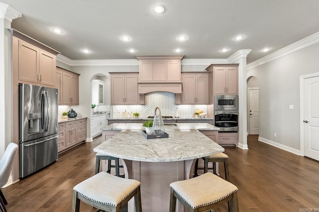 kitchen featuring light stone counters, a kitchen breakfast bar, decorative backsplash, a kitchen island with sink, and appliances with stainless steel finishes