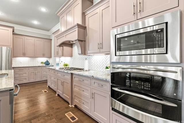 kitchen with light stone countertops, ornamental molding, backsplash, and appliances with stainless steel finishes