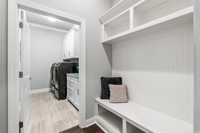 washroom with ornamental molding, cabinets, washing machine and clothes dryer, and hardwood / wood-style flooring