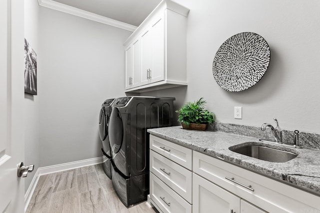 laundry area with sink, cabinets, light hardwood / wood-style flooring, washing machine and dryer, and crown molding