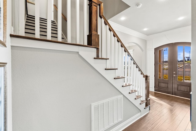 entryway with ornamental molding, french doors, and hardwood / wood-style floors