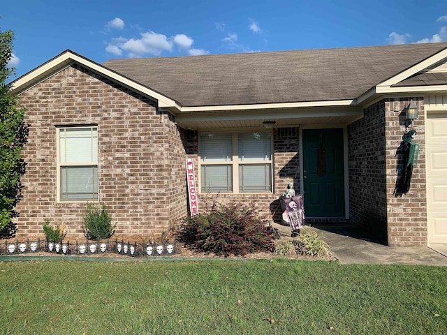 view of exterior entry with a yard and a garage