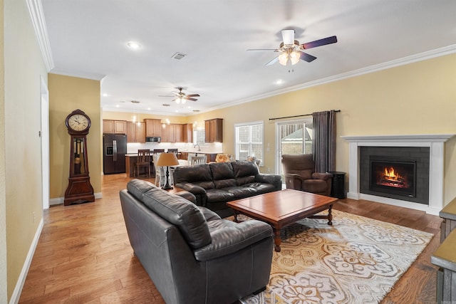 living room featuring ceiling fan, ornamental molding, and light hardwood / wood-style floors