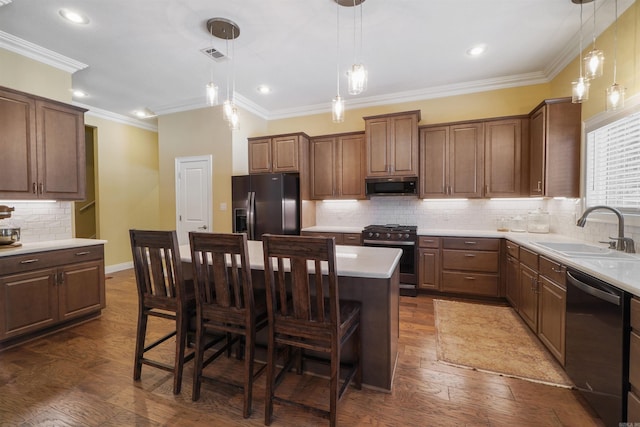 kitchen featuring appliances with stainless steel finishes, hanging light fixtures, sink, and a kitchen island