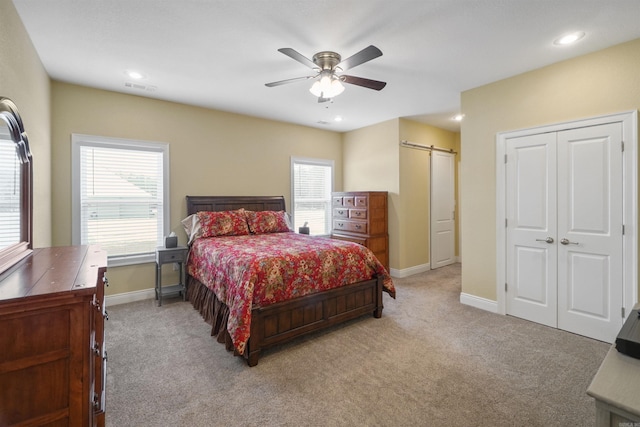 bedroom with a barn door, light colored carpet, and ceiling fan