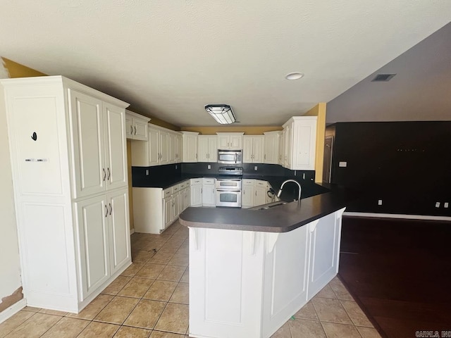 kitchen featuring sink, light tile patterned floors, kitchen peninsula, a breakfast bar, and appliances with stainless steel finishes