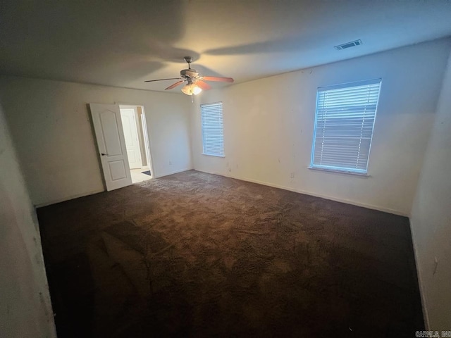 empty room featuring ceiling fan and dark carpet