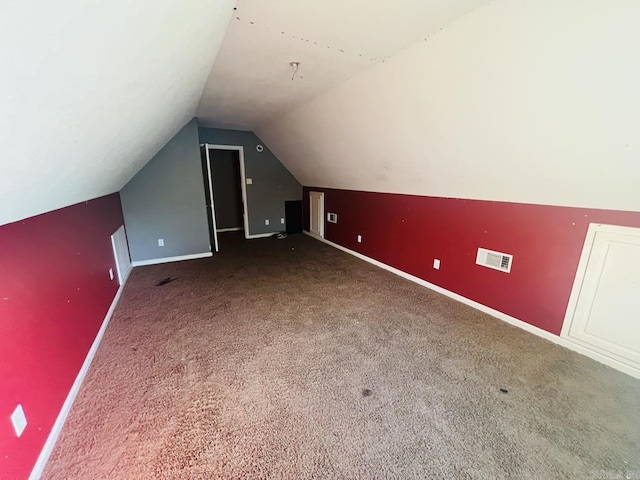 bonus room with vaulted ceiling and dark carpet