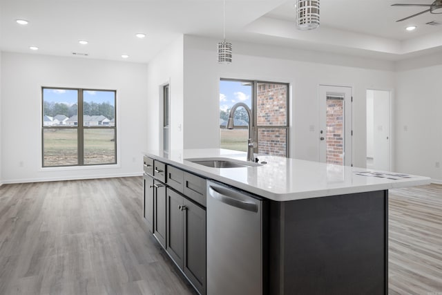 kitchen featuring light hardwood / wood-style floors, an island with sink, pendant lighting, sink, and stainless steel dishwasher