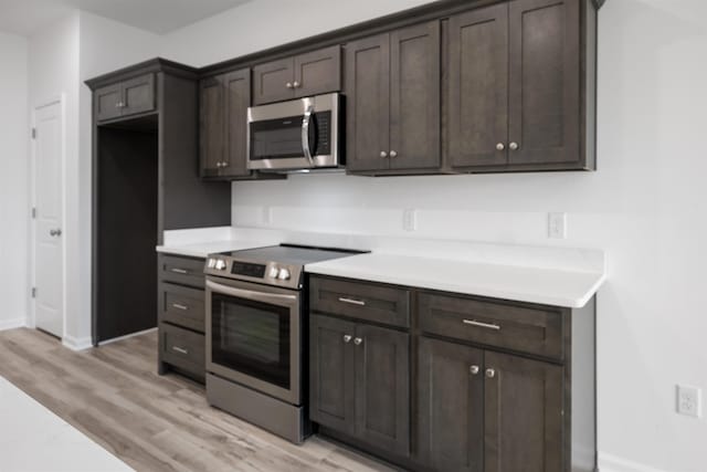 kitchen featuring appliances with stainless steel finishes, light hardwood / wood-style floors, and dark brown cabinetry