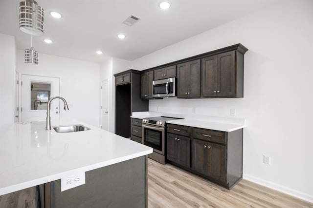 kitchen featuring appliances with stainless steel finishes, dark brown cabinetry, hanging light fixtures, and sink