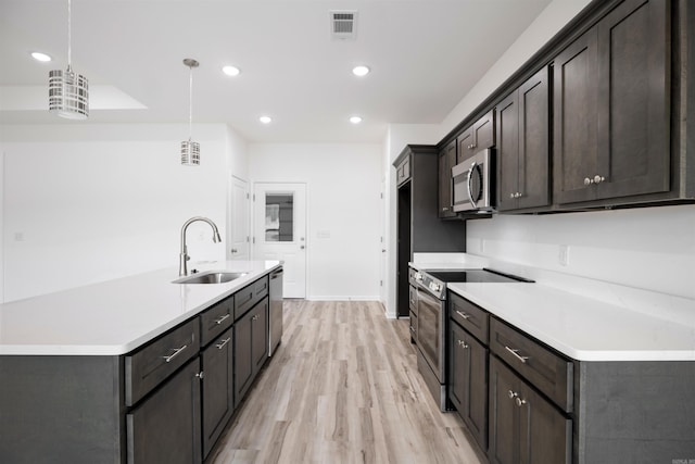 kitchen featuring sink, decorative light fixtures, light wood-type flooring, dark brown cabinetry, and appliances with stainless steel finishes