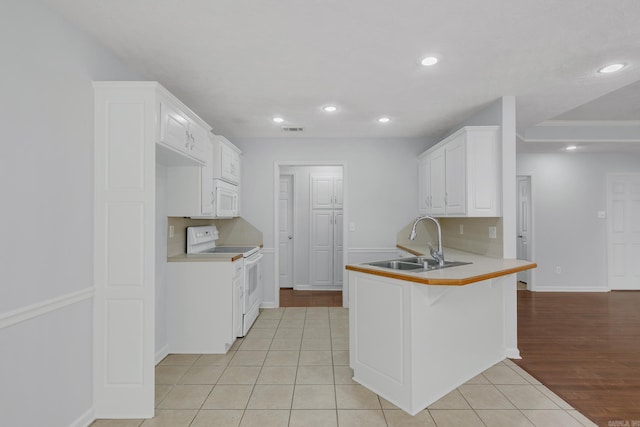 kitchen with sink, white cabinetry, white appliances, light tile patterned floors, and kitchen peninsula