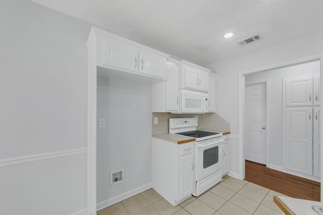 kitchen featuring white appliances, white cabinetry, backsplash, and light tile patterned floors