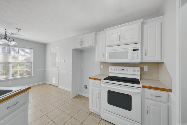 kitchen with white appliances, white cabinetry, light tile patterned floors, and a notable chandelier