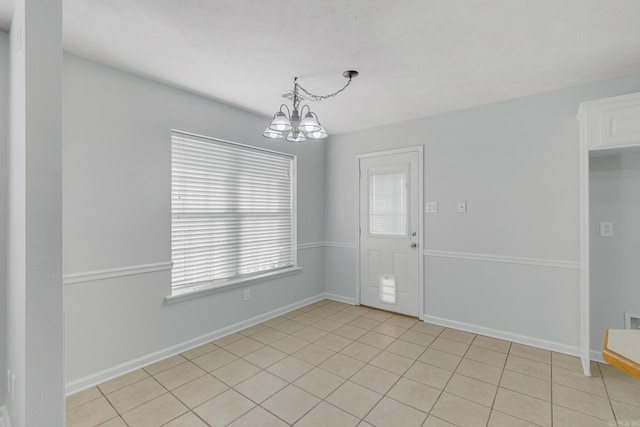 tiled spare room with a chandelier