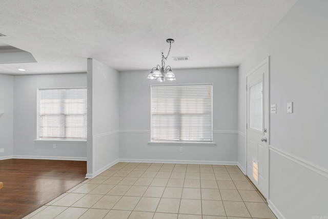 empty room with an inviting chandelier and light tile patterned floors