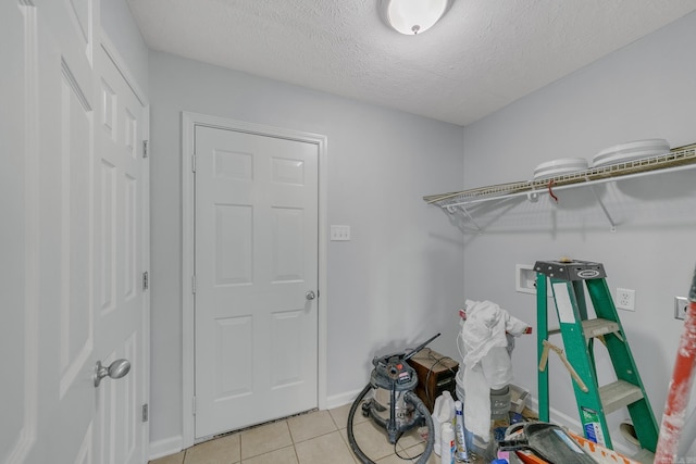 laundry area with a textured ceiling, washer hookup, and light tile patterned floors