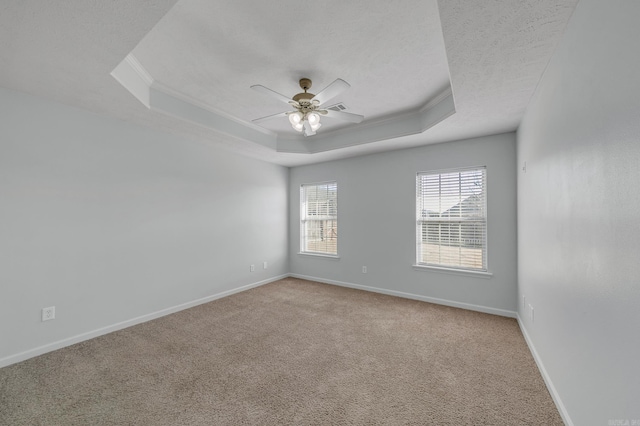 carpeted spare room featuring ornamental molding, ceiling fan, a textured ceiling, and a tray ceiling