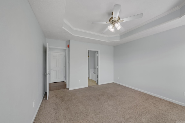 unfurnished bedroom with a raised ceiling, connected bathroom, ceiling fan, ornamental molding, and light carpet