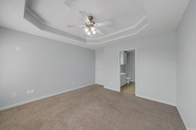 spare room with a raised ceiling, ceiling fan, crown molding, and light colored carpet