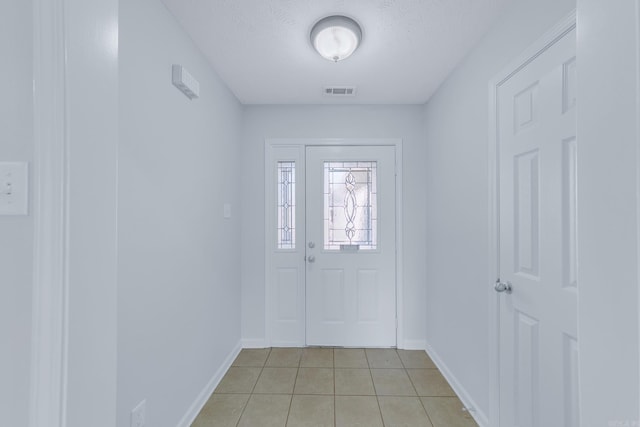 foyer entrance with a textured ceiling and light tile patterned floors