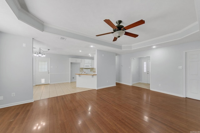 unfurnished living room with crown molding, a tray ceiling, and light hardwood / wood-style flooring