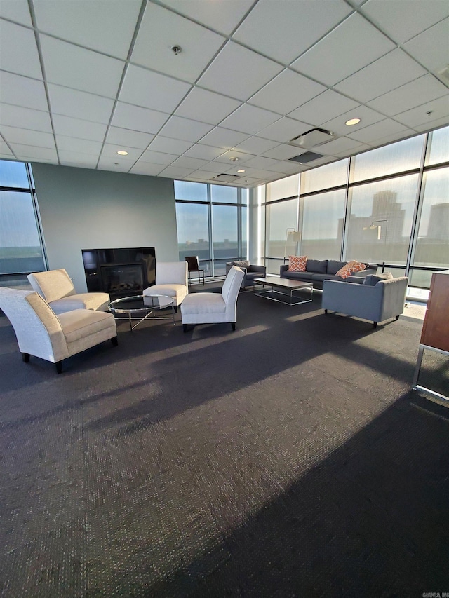 living room featuring carpet floors and a drop ceiling