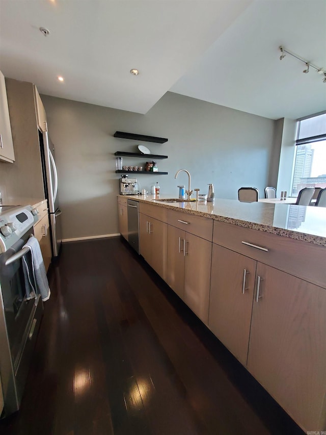 kitchen featuring stainless steel appliances, sink, light stone counters, light brown cabinets, and dark hardwood / wood-style flooring