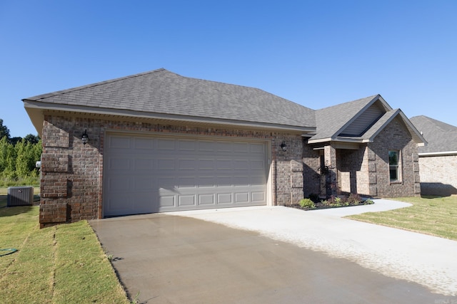 view of front of house with a garage, cooling unit, and a front lawn