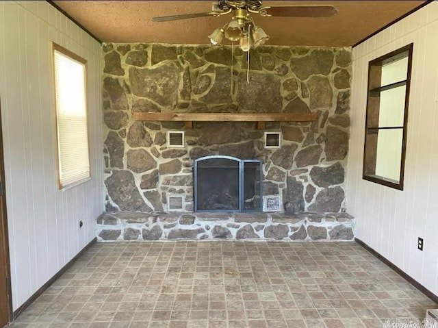 room details featuring wood walls, ceiling fan, and a stone fireplace