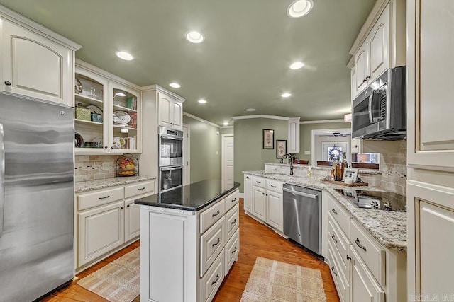 kitchen featuring white cabinets, kitchen peninsula, light hardwood / wood-style flooring, backsplash, and appliances with stainless steel finishes