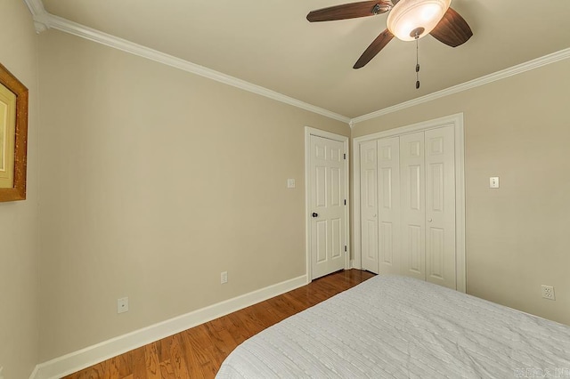 bedroom with ceiling fan, a closet, crown molding, and wood-type flooring