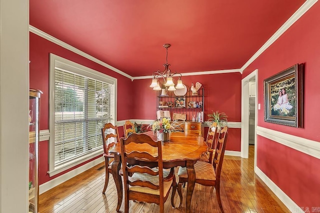 dining space with ornamental molding, a notable chandelier, and hardwood / wood-style flooring