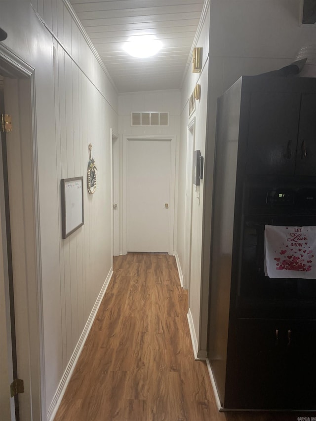 corridor featuring wood-type flooring and ornamental molding