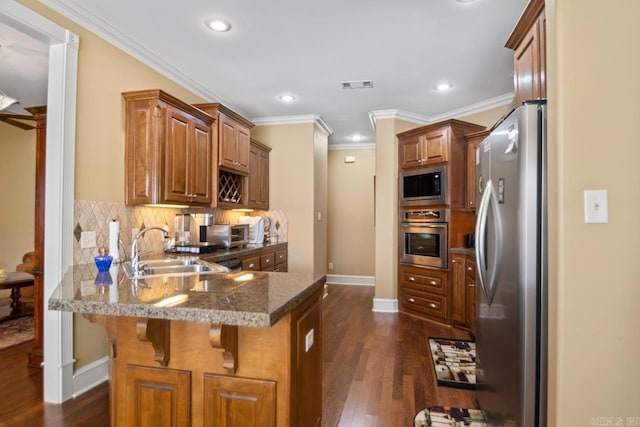 kitchen with kitchen peninsula, decorative backsplash, a breakfast bar area, appliances with stainless steel finishes, and sink