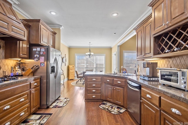 kitchen with ornamental molding, tasteful backsplash, light wood-type flooring, pendant lighting, and appliances with stainless steel finishes