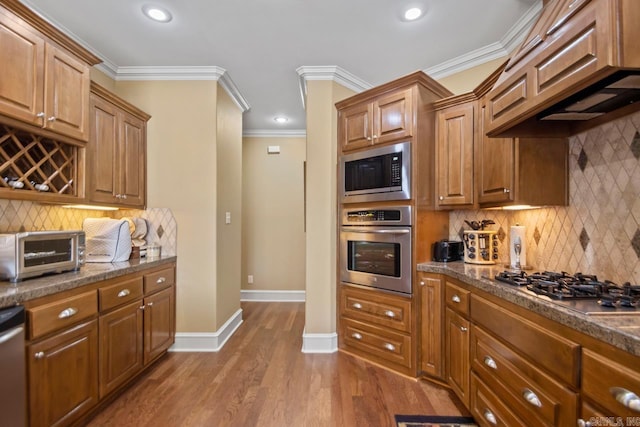 kitchen featuring appliances with stainless steel finishes, ornamental molding, backsplash, and hardwood / wood-style floors