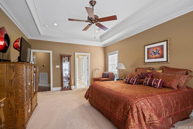 carpeted bedroom featuring ornamental molding, ceiling fan, a tray ceiling, and ensuite bathroom