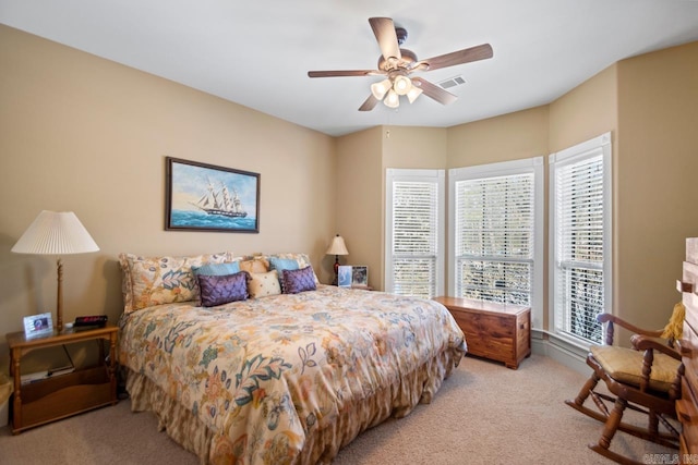 bedroom featuring multiple windows, light carpet, and ceiling fan