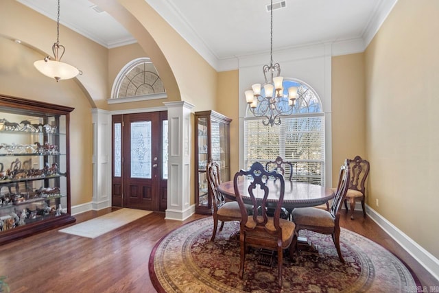 dining room with ornamental molding, dark hardwood / wood-style flooring, decorative columns, and a chandelier