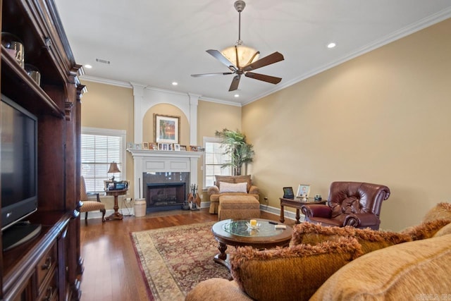 living room with dark hardwood / wood-style flooring, a high end fireplace, ornamental molding, and a wealth of natural light