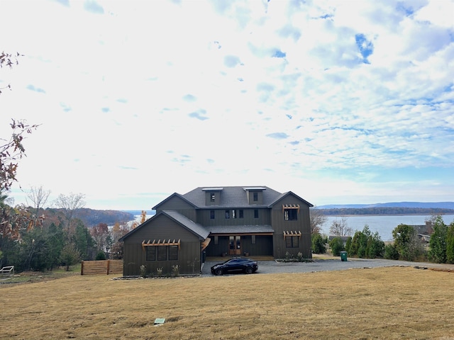 back of property featuring a lawn and a water and mountain view