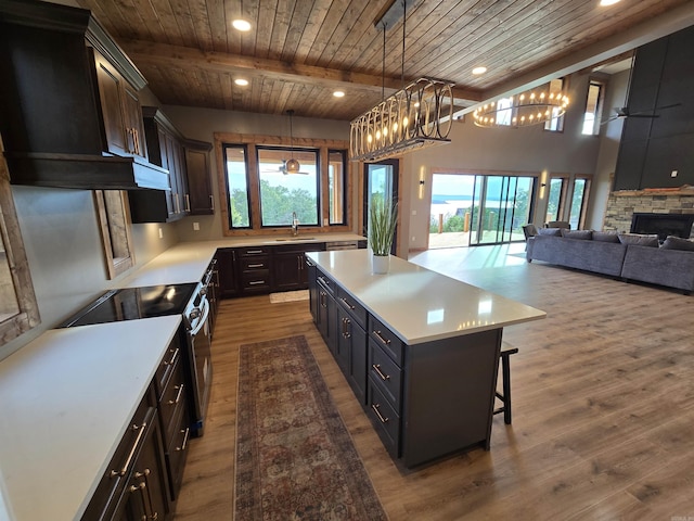 kitchen with sink, wooden ceiling, a fireplace, a kitchen island, and beam ceiling