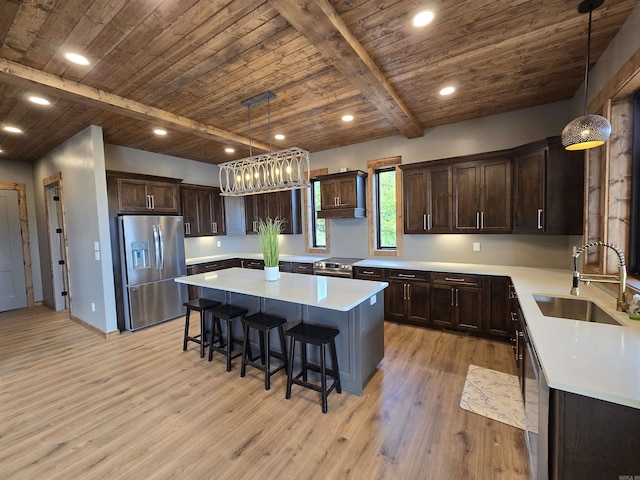 kitchen with stainless steel appliances, a center island, beam ceiling, decorative light fixtures, and sink