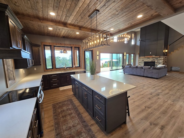 kitchen with pendant lighting, a center island, beam ceiling, a fireplace, and wooden ceiling